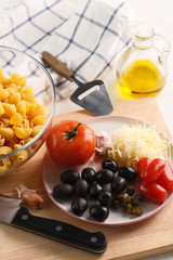 cooking pasta. Ingredients: tomatoes, Parmesan, olives and pasta.