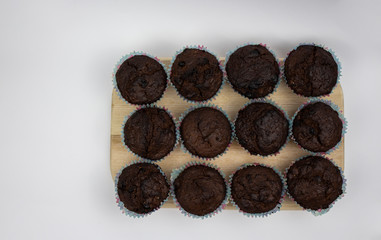 Chocolate Banana Muffins on a wooden board against a white background. View from above. Copy space