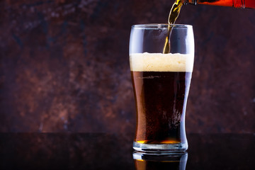 glass of beer with foam on a dark background