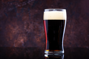 glass of beer with foam on a dark background