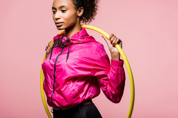 attractive african american sportswoman posing with hula hoop isolated on pink