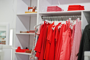 Female red colorful clothing set of on the racks and shelves in clothing store brand new modern boutique. Spring summer dress collections.