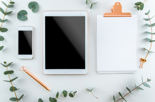 Top view workspace, notebook, blank clipboard, pen. Freelancer workplace concept. Mockup mobile cell phone and tablet gadget. White isolated flat lay, copy space
