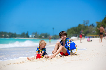 Fototapeta na wymiar Happy beautiful fashion family, mom and children, dressed in hawaiian shirts, playing together on the beach