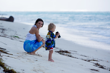 Mom, holding little toddler boy with binoculars, observing dolphins
