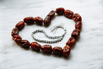 heart shaped by dates and white rosary for Ramadan and Friday message concept.