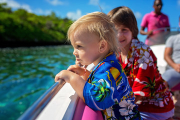Happy beautiful fashion family, children and parents, dressed in hawaiian shirts, enjoying day trip with speed boat