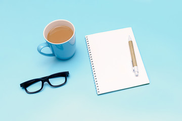 coffee, notebook and glasses on blue background