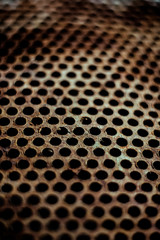 Perforated brown rusty iron sheet texture. Surface with depth of field, industrial mesh. Vertical background
