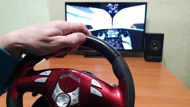 The Gamer races in the game. Gamer behind the steering wheel in a racing simulator.