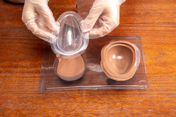 Homemade Easter egg factory. Making eggshell from easter egg with melted chocolate and a shape.