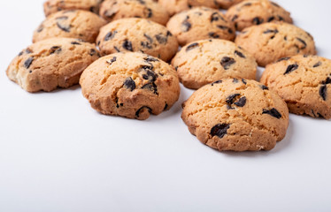 lots of cookies with chips and pieces of chocolate on white background