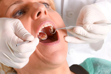 Dentist with white latex gloves examining a woman