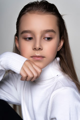 Portrait of a cute teen girl wearing a white turtleneck sweater. Isolated on gray background. Advertising, trendy and commercial design. Copy space