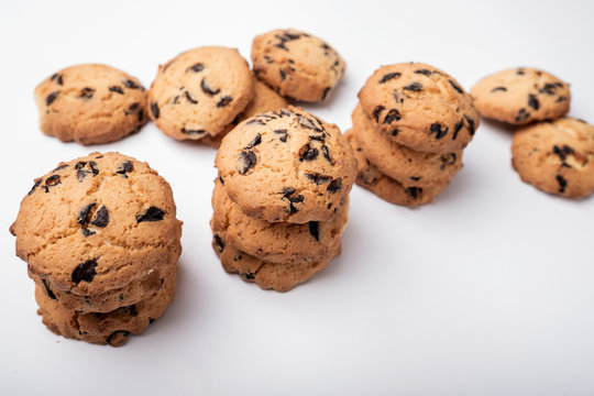 lots of cookies with chips and pieces of chocolate on white background