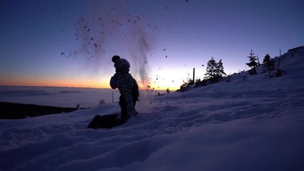 Kind wirft Schnee im Abendlicht auf einem Berg, Zeitlupe