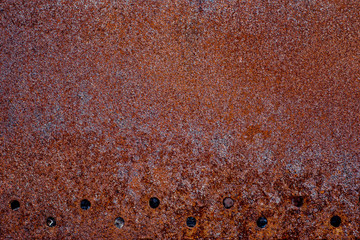 Texture of completely rusty metal with row of holes in down side