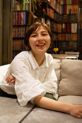 Asian chinese girl having a good time at a coffee shop in hangzhou, China. wearing a white shirt, smiling