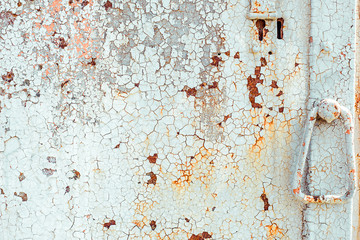 Texture of rusty metal door with handle, painted white which became orange from rust in some places. Horizontal texture of cracked white paint