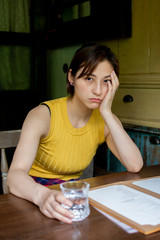 Asian chinese girl having a good time at a coffee shop in hangzhou, China. wearing a yellow tank top and a reddish patterned dress with pants. holding a hand bag