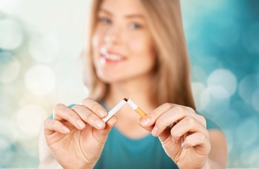 Young woman breaking cigarette  on background