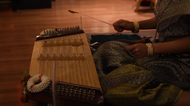 Close-up of Thai or chinese musician playing a traditional zither khim musical instrument