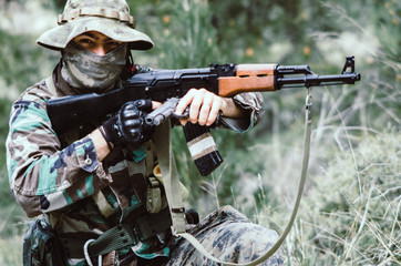 Fototapeta premium Special forces soldier holding hand gun and knife in crouching shooting position