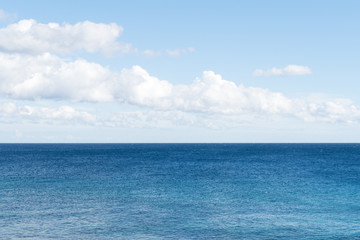 Clean, clear beautiful deep blue Atlantic Ocean backdrop wallpaper against a blue sky with few clouds and lots of copy space. 