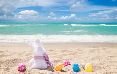 Easter bunny with color eggs on the ocean beach - 260332666