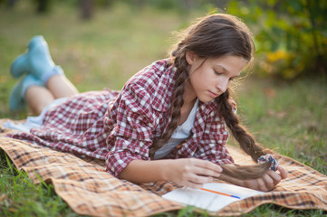 The girl sitting under the tree and wrote in Notepad