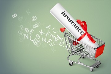 Paper bundle with word insurance and ribbon in toy shopping cart on background