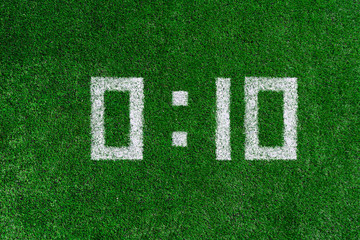 White numbers zero and ten are drawn on the green grass, football score