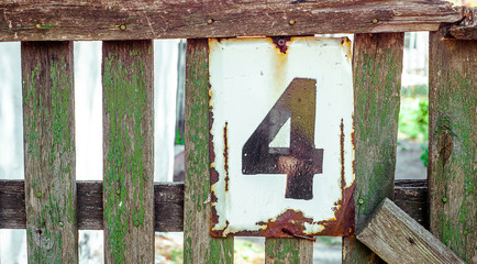 White Shabby And Rusty Metal Plate With Black Nuber Four, Nailed On Green Fence
