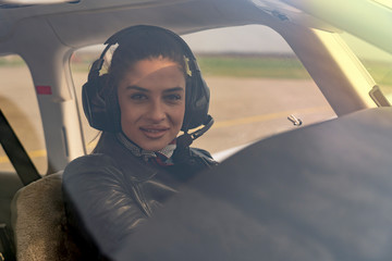 Beautiful Young Woman Pilot With Headset Looking Through The Cockpit Window