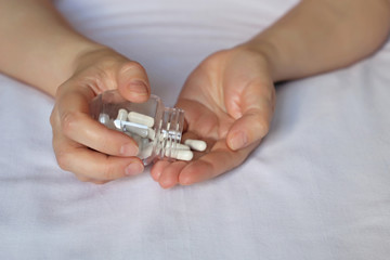 Woman with pills, female hands on the bed with a tablets in capsules. Concept of pharmacy, diet...