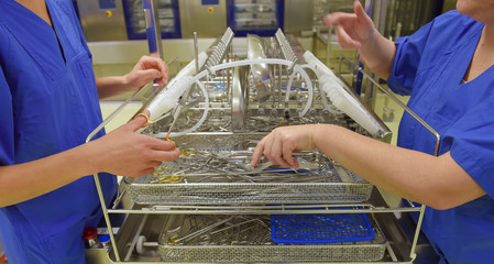 Two women work in a hospital as hygiene medical  technicians. They are dressed in special medical hygiene  clothing. They are seen carrying out hygiene  disinfecting and sterilization tasks.