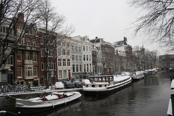 Snowy landscape in Amsterdam with boats on the river