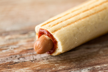 fast food and unhealthy eating concept - close up of hot dog on wooden table