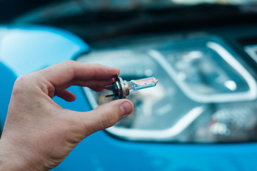 man hand changing light bulb on car headlight