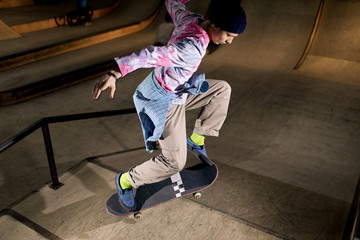 High angle action shot of contemporary young man doing skating stunt at skateboard park, shot with...