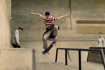 Action shot of contemporary young man doing stunts in skateboard park, copy space