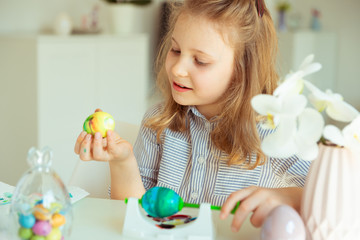 Obraz na płótnie Canvas Cute little blonde girl painting Easter eggs