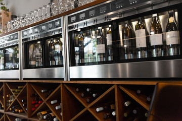 alcohol, technology and storage concept - close up of wine bottles storing in dispenser at bar or...