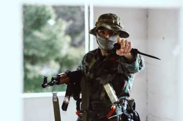 Blurry face Special forces soldier holding rifle gun point  finger at you looking at camera