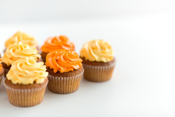 food, pastry and confectionery concept - cupcakes with buttercream frosting over white background
