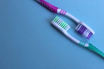 Two toothbrushes lie against each other on a blue background