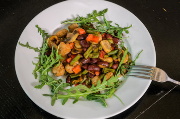 Vegetarian vegetable salad with mushrooms, arugula, carrots, beans and pepper
