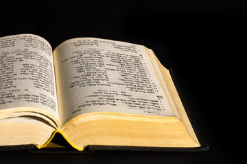 Fototapeta na wymiar Open hebrew Bible, isolated on black background, with front lighting