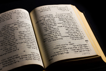 Fototapeta na wymiar Open hebrew Bible, isolated on black background, with side lighting