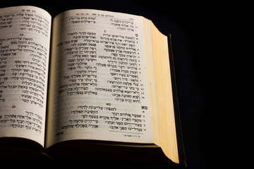 Open hebrew Bible, isolated on black background, with side lighting